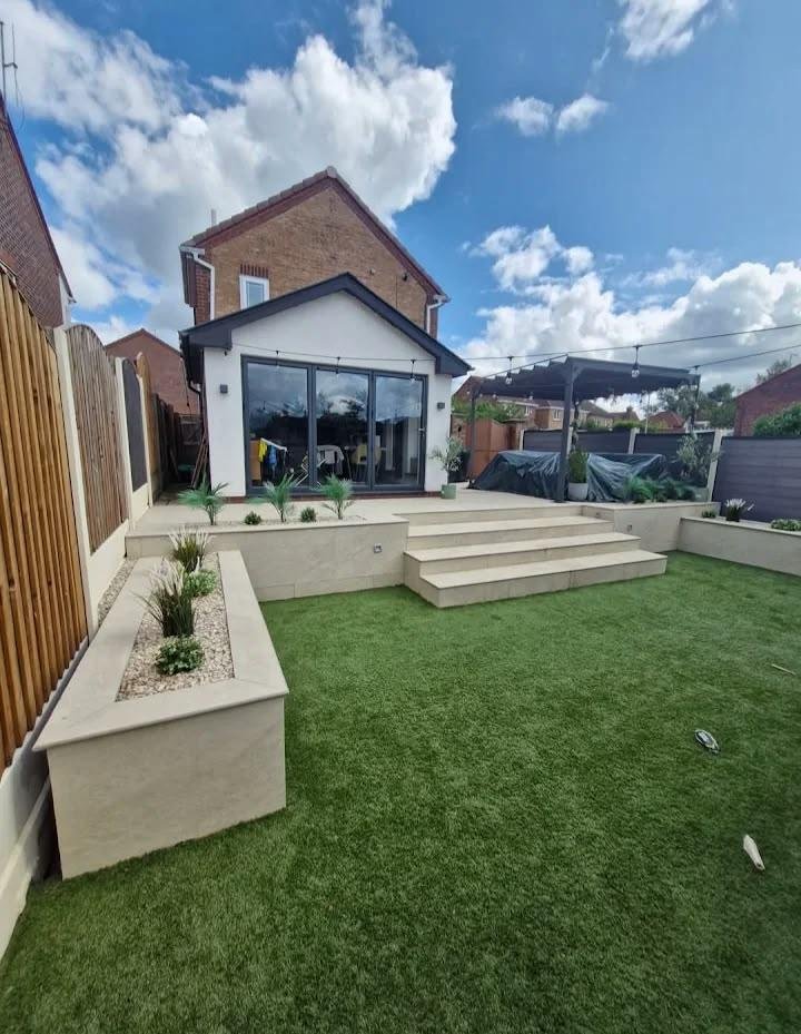 Modern cream porcelain paving patio with steps, raised planters and artificial lawn built by Kestrel Property Solutions landscapers